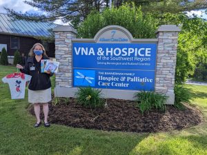 woman holding books and pajamas at VNA & Hospice sign on property